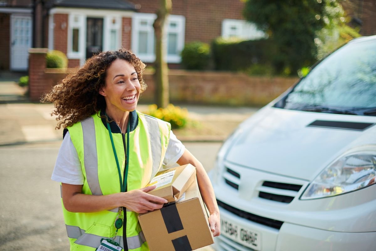Courier carrying parcels beside a delivery vehicle for same-day delivery services